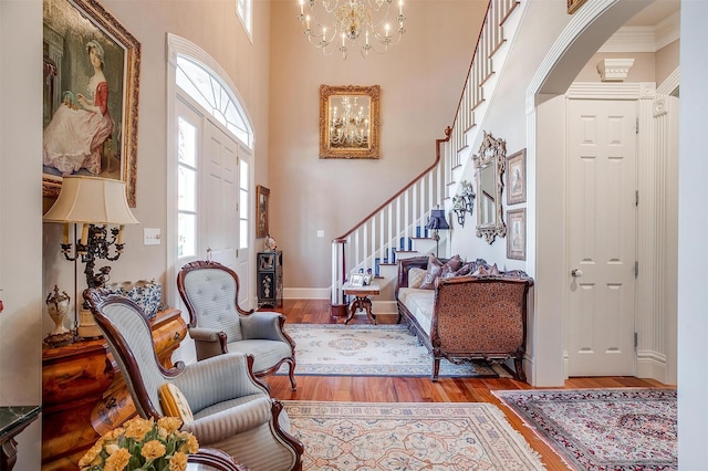 entrance foyer featuring hardwood / wood-style floors, a towering ceiling, crown molding, and a notable chandelier