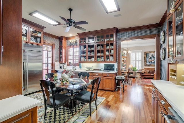 dining room featuring ceiling fan with notable chandelier, light wood-type flooring, a wealth of natural light, and ornamental molding