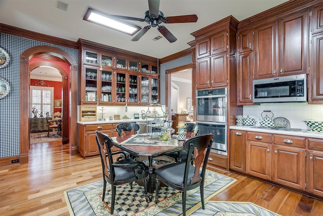 kitchen featuring ceiling fan, light hardwood / wood-style floors, appliances with stainless steel finishes, and tasteful backsplash