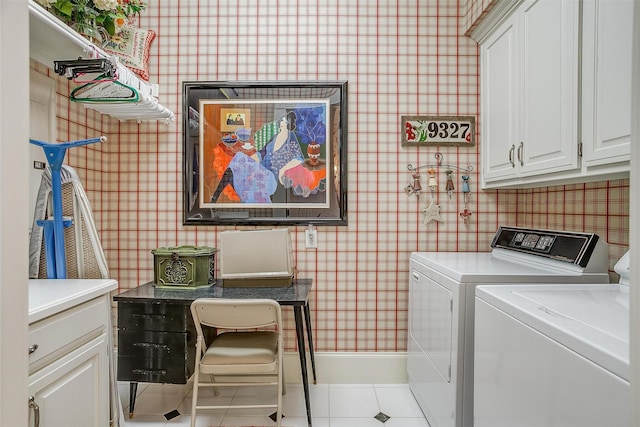 washroom featuring washing machine and clothes dryer, light tile patterned floors, and cabinets