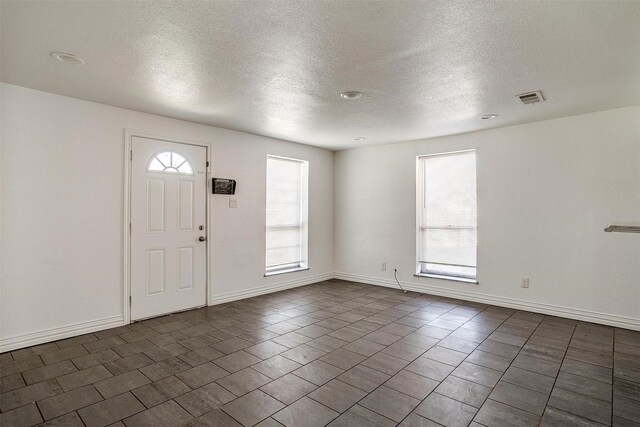 tiled foyer entrance featuring a healthy amount of sunlight and a textured ceiling