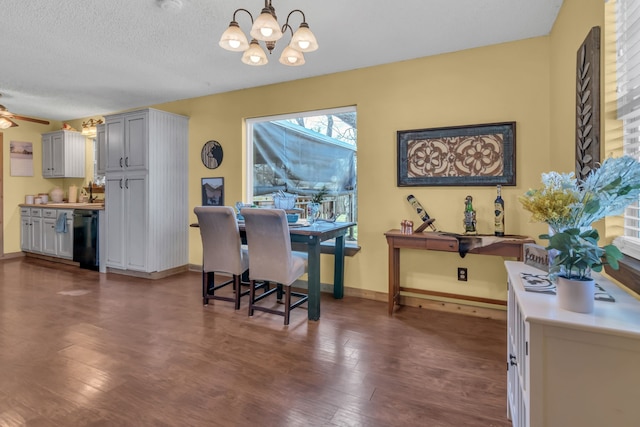 dining space with dark hardwood / wood-style flooring, ceiling fan with notable chandelier, and a textured ceiling