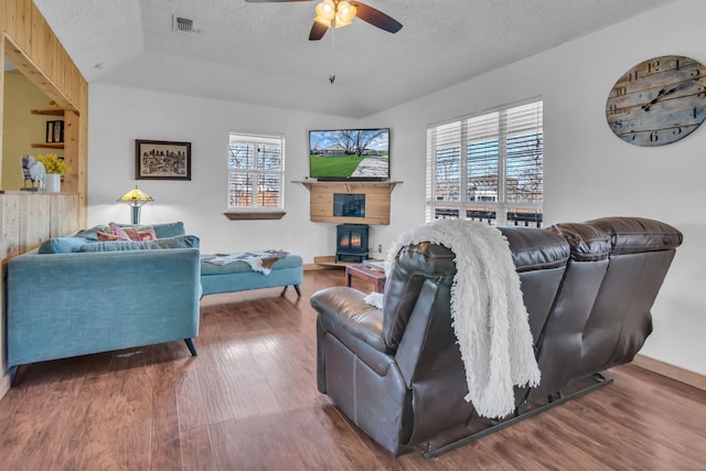 living room featuring ceiling fan, wood-type flooring, a fireplace, and a textured ceiling