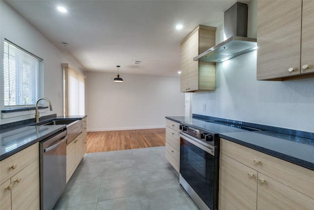 kitchen with wall chimney range hood, hanging light fixtures, sink, light brown cabinetry, and appliances with stainless steel finishes