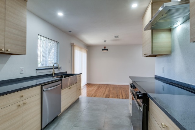 kitchen featuring wall chimney exhaust hood, stainless steel appliances, sink, light brown cabinets, and hanging light fixtures