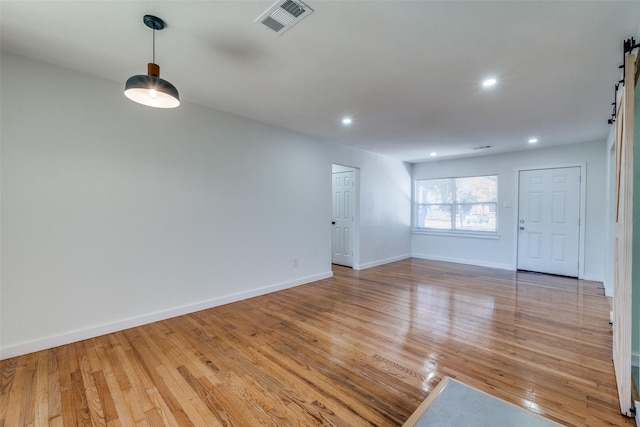 unfurnished room featuring a barn door and light wood-type flooring