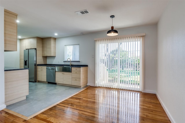 kitchen with sink, hanging light fixtures, light hardwood / wood-style flooring, light brown cabinetry, and appliances with stainless steel finishes