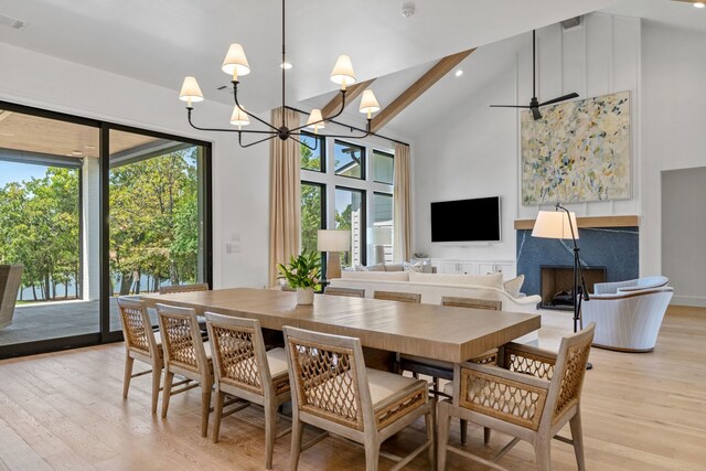 dining area with high vaulted ceiling, beamed ceiling, ceiling fan with notable chandelier, and light hardwood / wood-style flooring