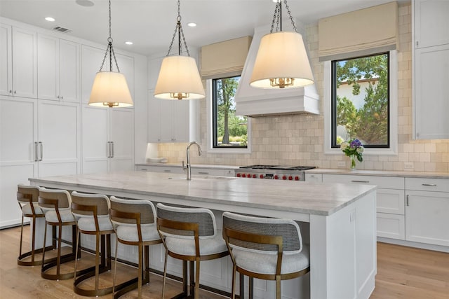 kitchen with white cabinetry, an island with sink, and sink