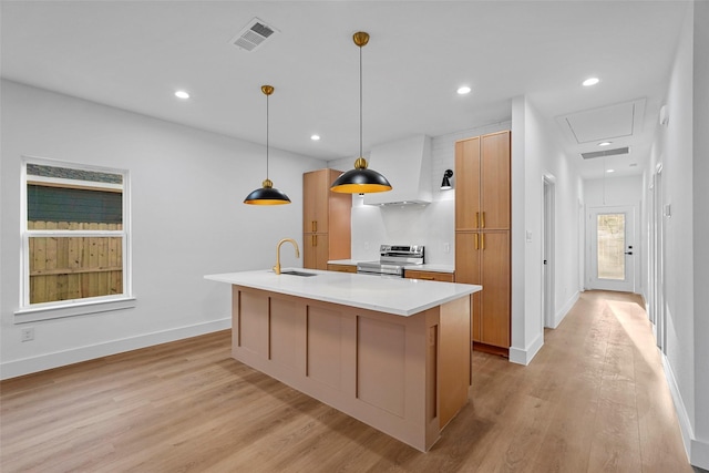 kitchen featuring light wood-type flooring, sink, electric stove, decorative light fixtures, and a center island with sink