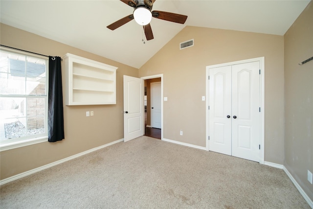 unfurnished bedroom with vaulted ceiling, light colored carpet, a closet, and ceiling fan