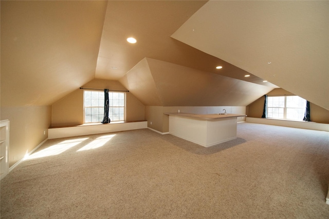 additional living space with lofted ceiling, sink, and carpet floors