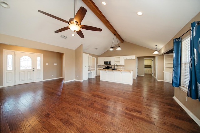 unfurnished living room with ceiling fan, dark hardwood / wood-style flooring, and vaulted ceiling with beams