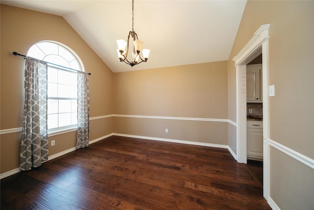 spare room featuring vaulted ceiling, an inviting chandelier, a wealth of natural light, and dark hardwood / wood-style floors