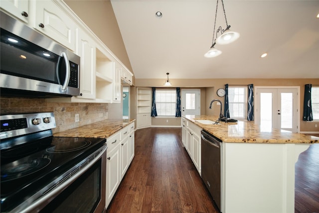 kitchen with pendant lighting, appliances with stainless steel finishes, a kitchen island with sink, light stone countertops, and white cabinets