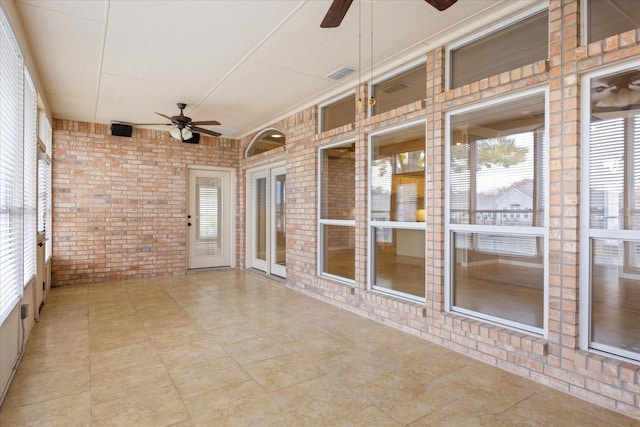 unfurnished sunroom featuring ceiling fan and a wealth of natural light