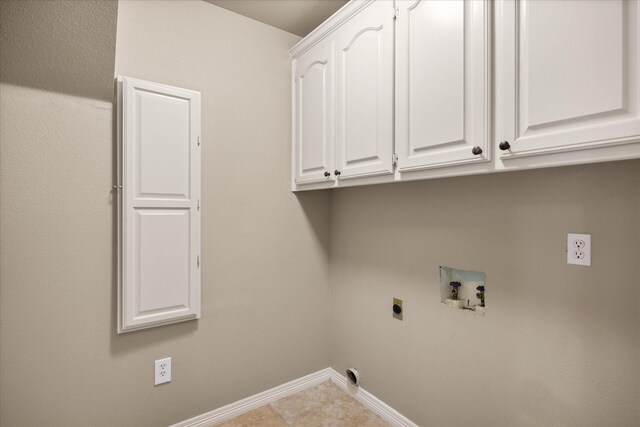 laundry area with electric dryer hookup, hookup for a washing machine, light tile patterned floors, and cabinets