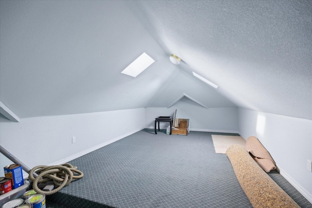 bonus room with lofted ceiling with skylight, a textured ceiling, and dark colored carpet