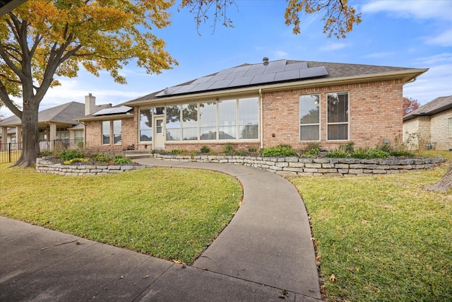 rear view of property with a yard and solar panels