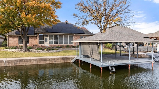 view of dock with a gazebo, a lawn, and a water view