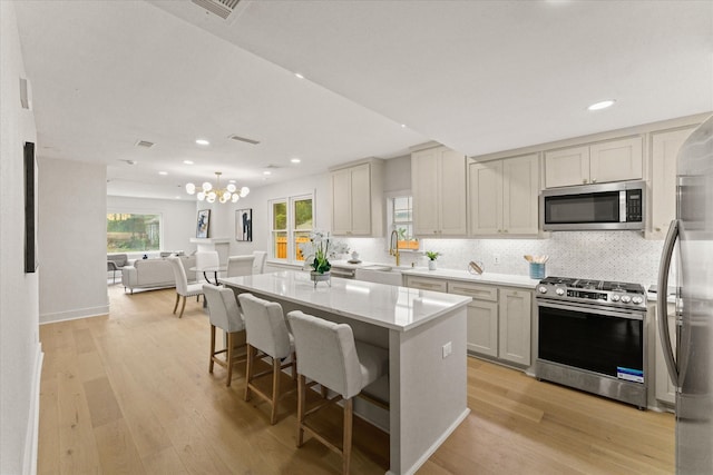 kitchen with a breakfast bar, sink, a center island, light wood-type flooring, and appliances with stainless steel finishes