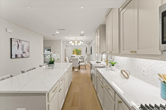 kitchen featuring tasteful backsplash, white cabinetry, light hardwood / wood-style flooring, and light stone countertops