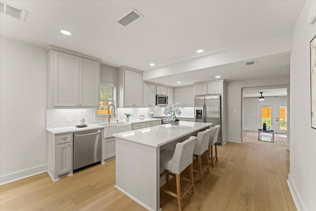 kitchen featuring a kitchen breakfast bar, stainless steel appliances, sink, light hardwood / wood-style flooring, and a center island