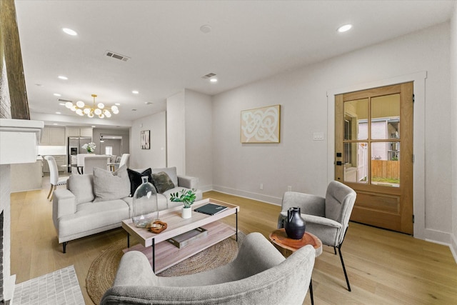 living room with light hardwood / wood-style floors and an inviting chandelier