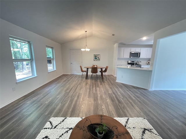 unfurnished living room featuring lofted ceiling, sink, a notable chandelier, and dark wood-type flooring