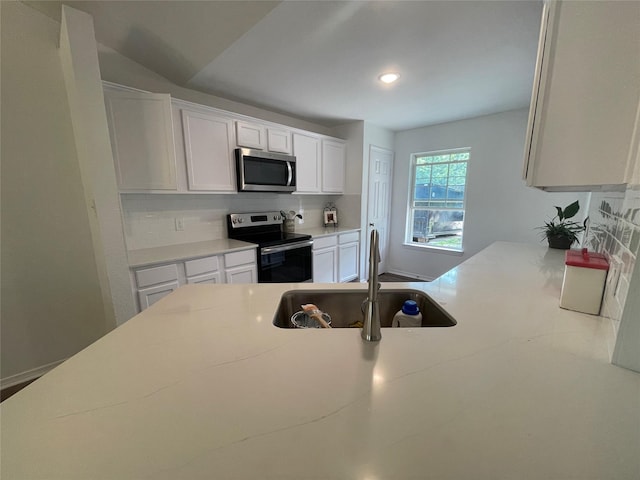 kitchen featuring white cabinets, sink, vaulted ceiling, decorative backsplash, and stainless steel appliances