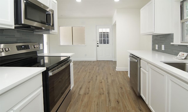 kitchen with stainless steel appliances, white cabinetry, tasteful backsplash, and light wood-type flooring