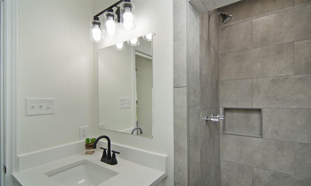 bathroom with tiled shower and vanity