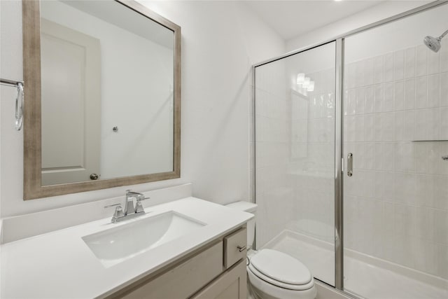 bathroom featuring a shower with door, vanity, and toilet