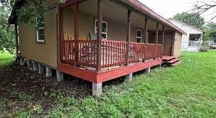 rear view of house featuring a yard and a wooden deck