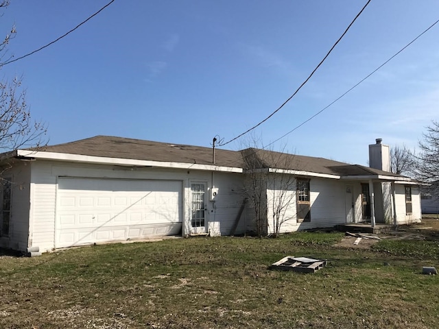 rear view of property featuring a garage and a yard