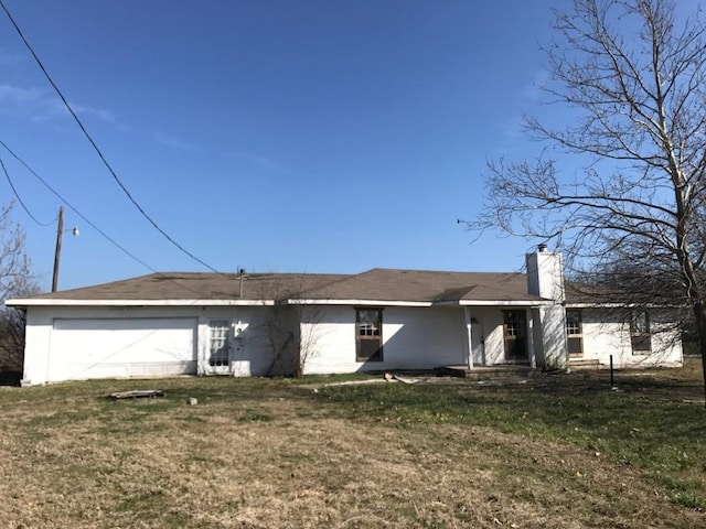 rear view of property with a yard and a garage