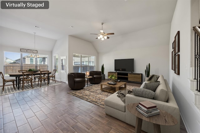 living room with ceiling fan with notable chandelier and vaulted ceiling