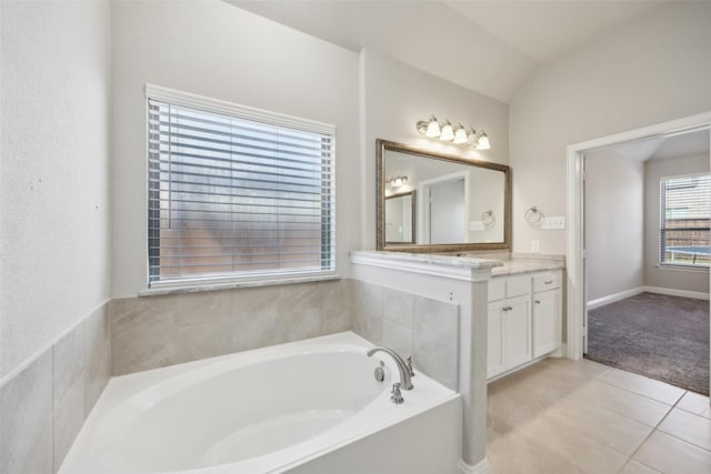 bathroom featuring tile patterned floors, a bathtub, vanity, and vaulted ceiling