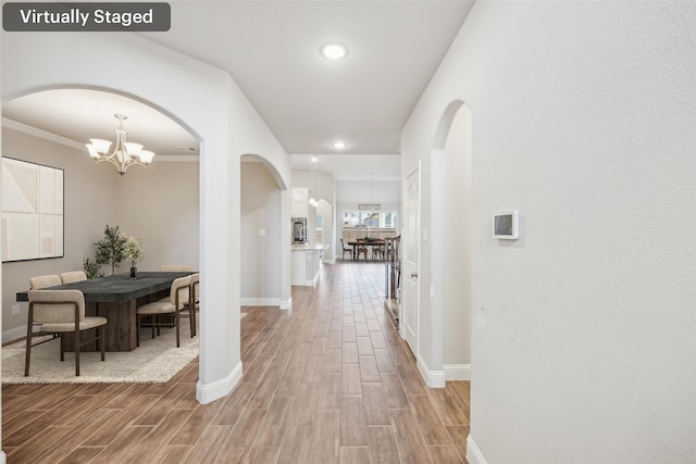 corridor featuring crown molding and a chandelier