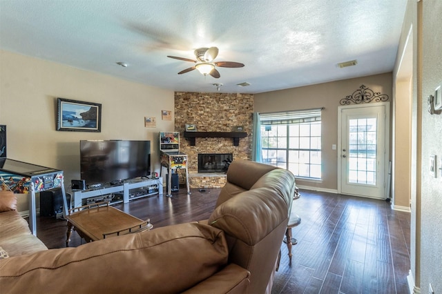 living area featuring dark wood-style floors, visible vents, a fireplace, and a textured ceiling