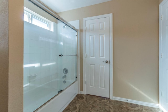 bathroom featuring enclosed tub / shower combo and baseboards