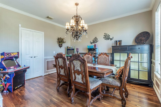 dining space with dark wood-type flooring, visible vents, ornamental molding, and an inviting chandelier