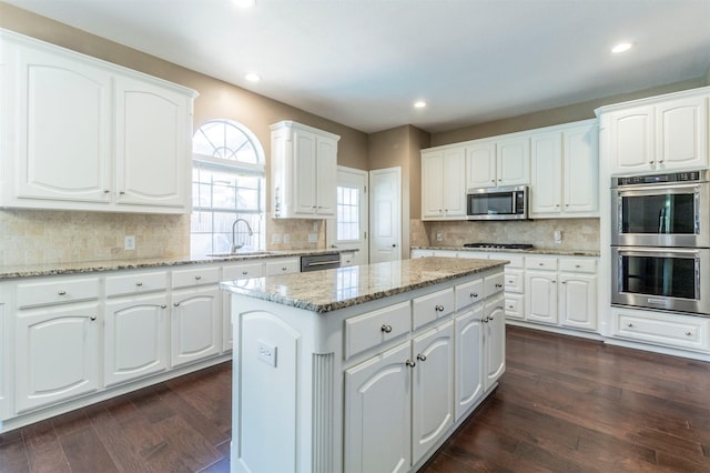 kitchen with appliances with stainless steel finishes, a sink, and white cabinetry