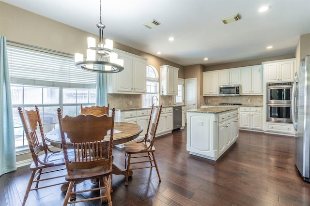 kitchen featuring white cabinets, visible vents, pendant lighting, and stainless steel appliances