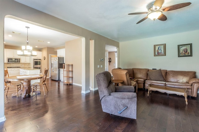 living area featuring dark wood-style floors, baseboards, and ceiling fan with notable chandelier