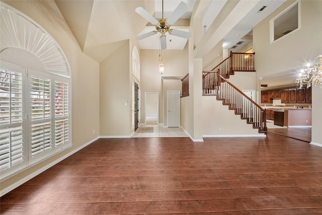 entrance foyer featuring a high ceiling, ceiling fan with notable chandelier, and dark wood-type flooring