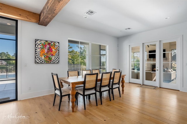 dining room featuring french doors, beam ceiling, and light hardwood / wood-style flooring