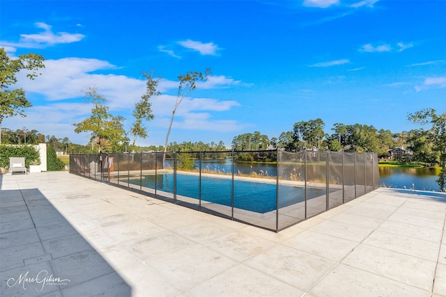 view of pool with a patio, a swimming pool, a water view, and fence