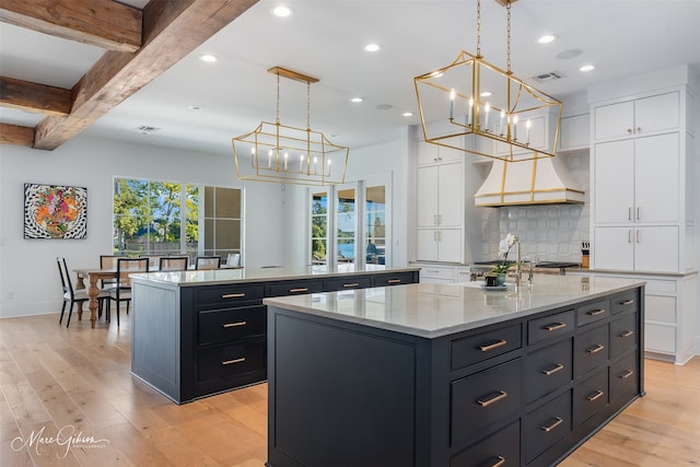 kitchen with a center island with sink, white cabinets, and dark cabinets