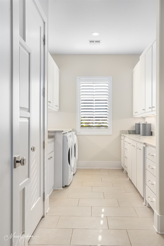 clothes washing area featuring cabinet space, visible vents, washing machine and dryer, light wood-type flooring, and baseboards